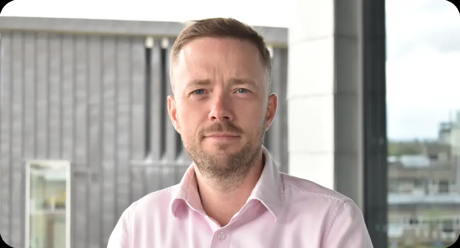 Gillies Kleboe, Founder of Kleboe, in a pale pink shirt in front of an office building